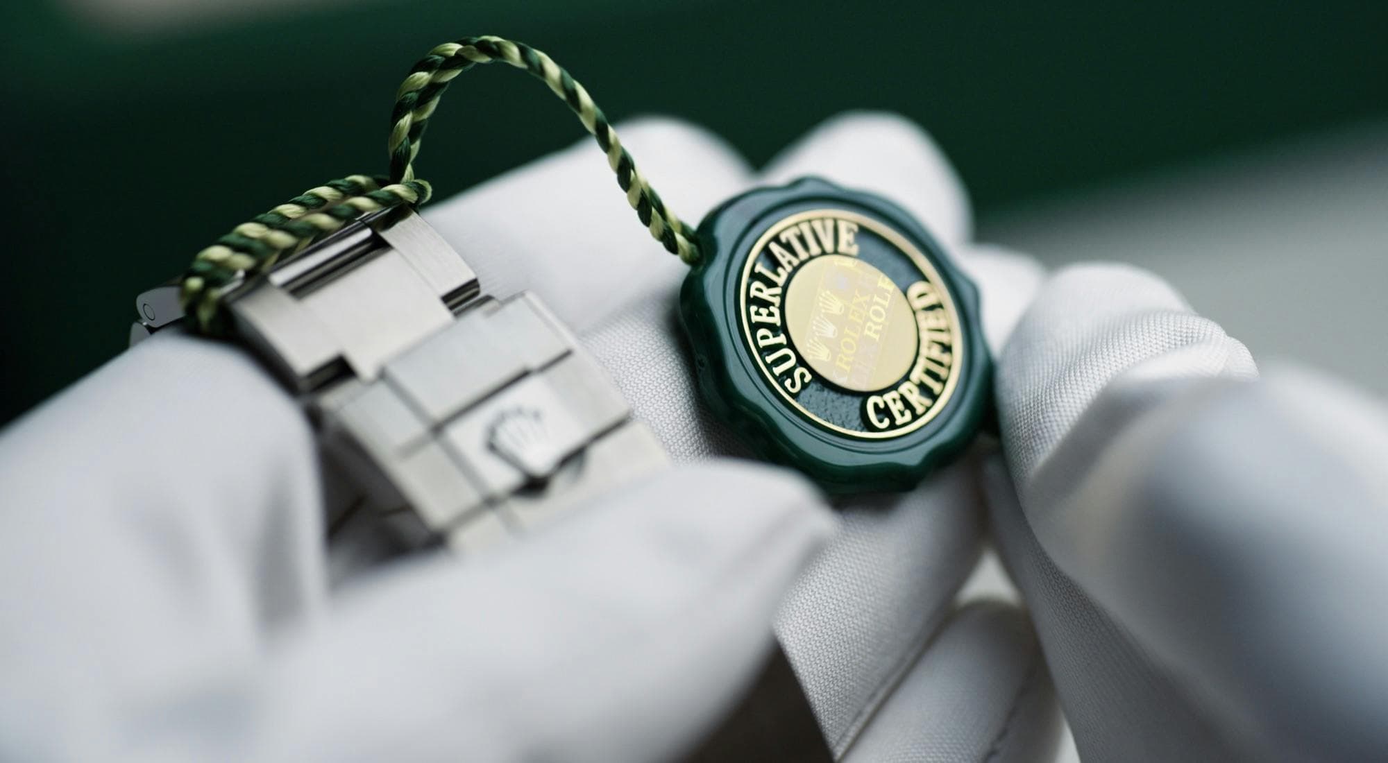 close up photo of two gloved hands holding a Rolex watch with a Superlative Certified seal