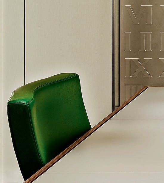 Signature Rolex green chair seated at a table in a Rolex Showroom at Lee Michaels Fine Jewelry.